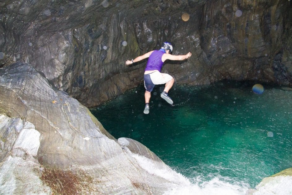 Man jumping off a waterfall at the Golden Grotto, a famous river tracing spot in Hualien, one of the best July things to do in Taiwan