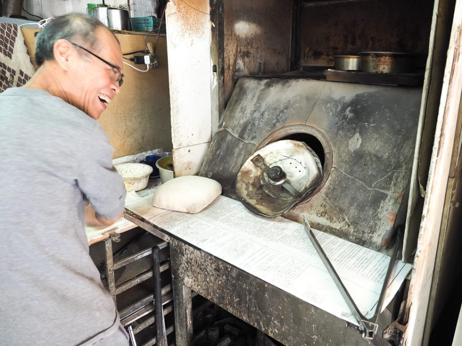 Owner of 786 Liyuan Halal Snacks (786李園清真小吃) putting Indian flatbreads into a tandoor-like oven