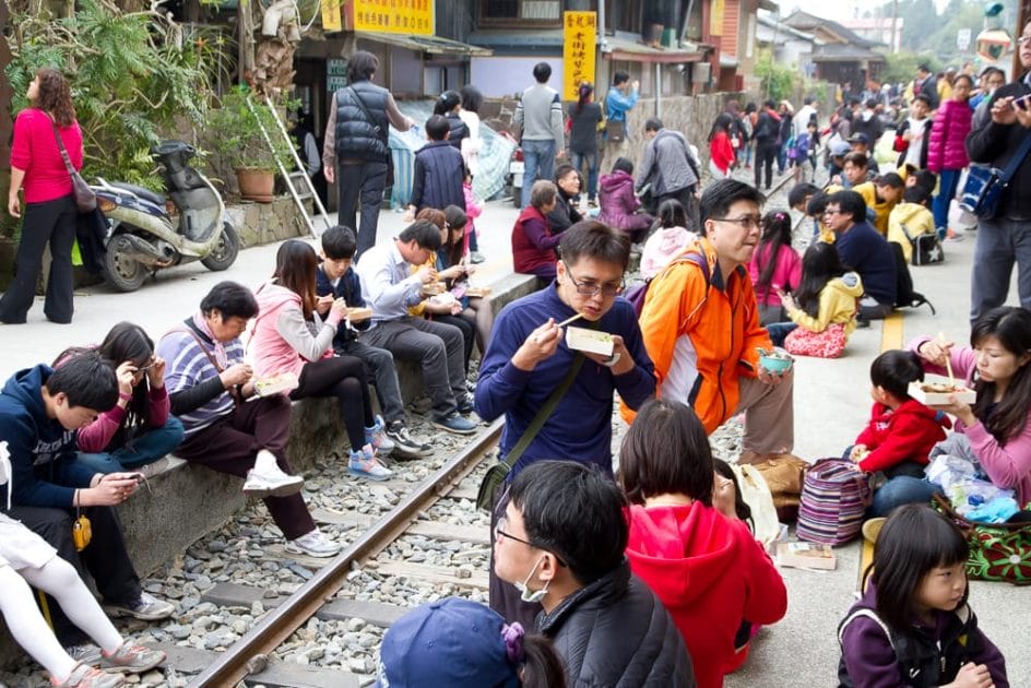 Taiwanese people eating Fenqihu lunchboxes on the train tracks at Fenqihu station