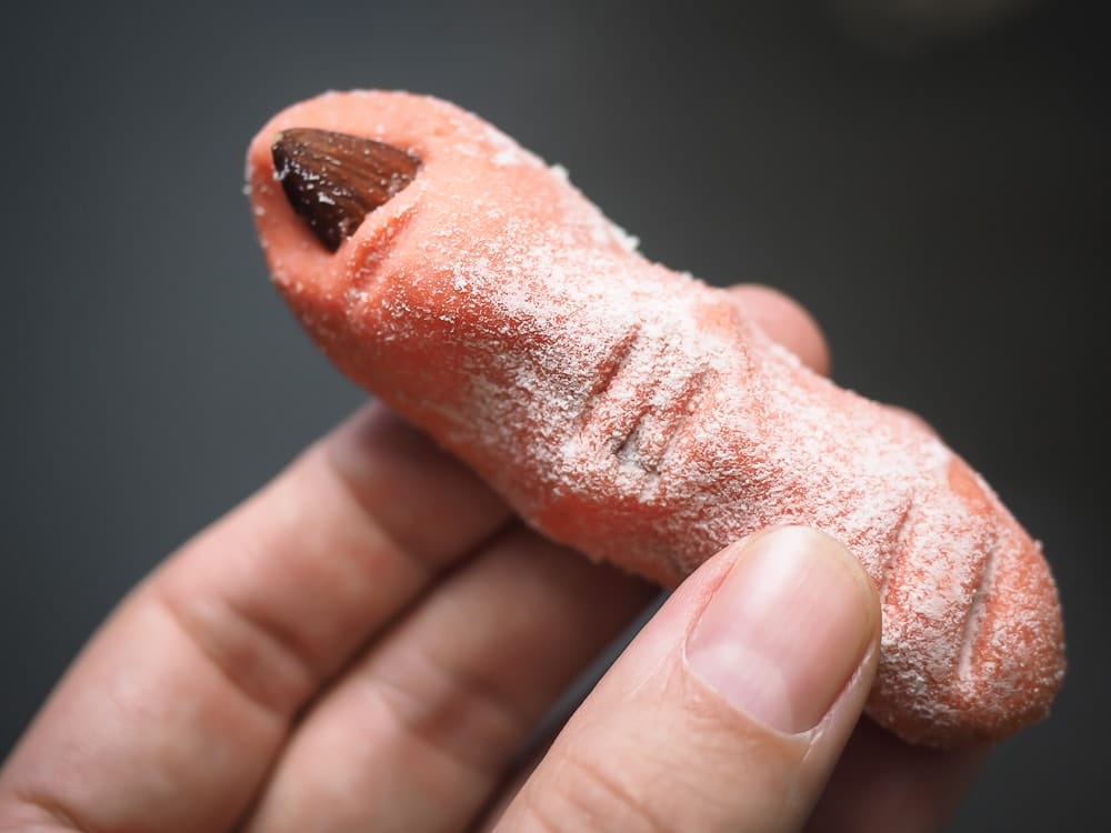 My daughter contemplating eating a strawberry-flavored witch's finger cookie.