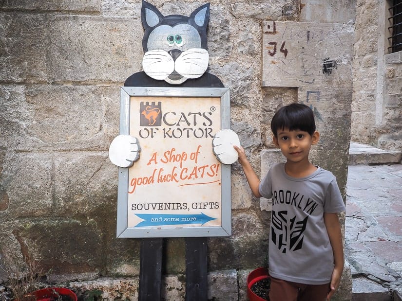 My son standing by the sign of the Cats of Kotor shop