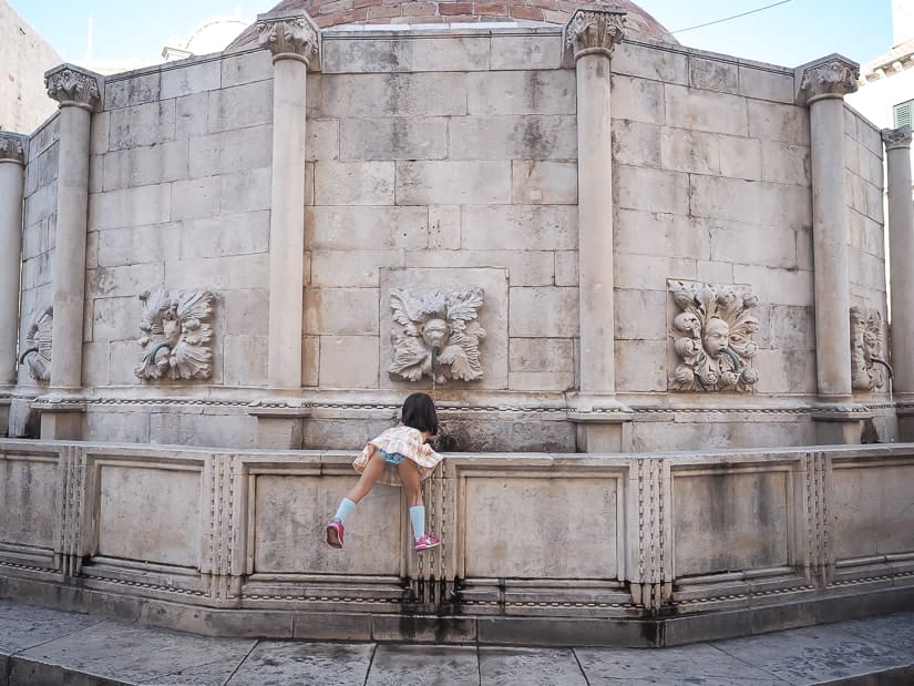 My daughter reaching in to the Jewish Fountain in Dubrovnik