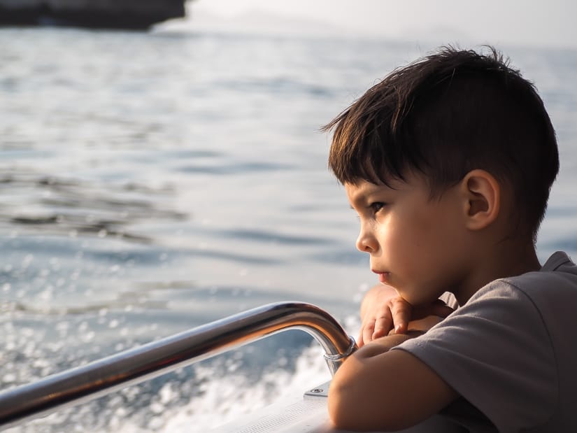 Sage watching for dolphins on our Oman boat tour with kids