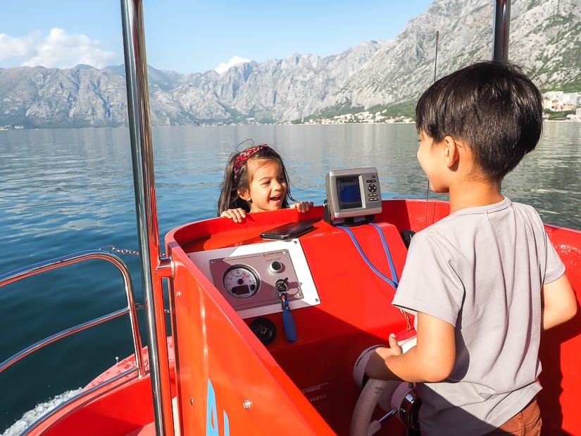 My son driving a boat on the Bay of Kotor, with my daughter facing him