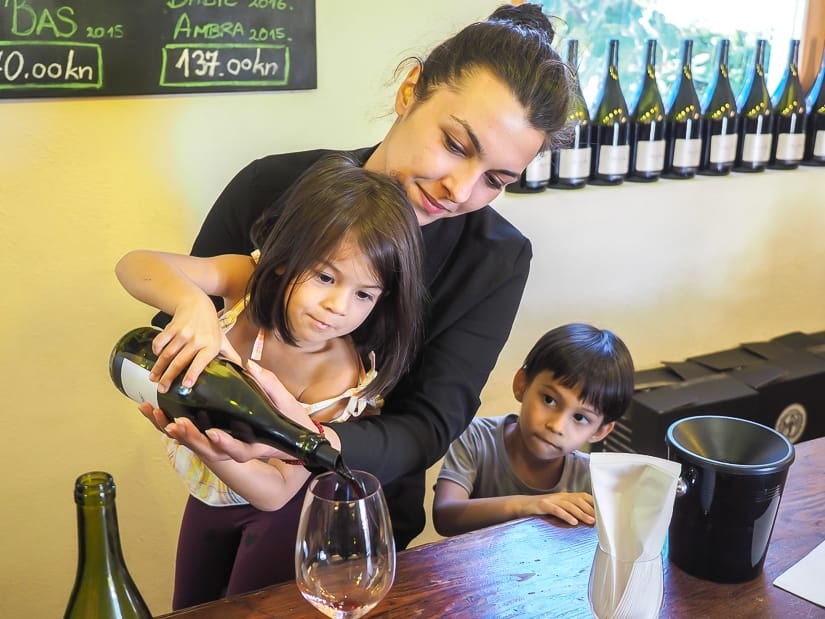 A woman helping a young girl to pour wine at Bibich winery, Plastova, Croatia