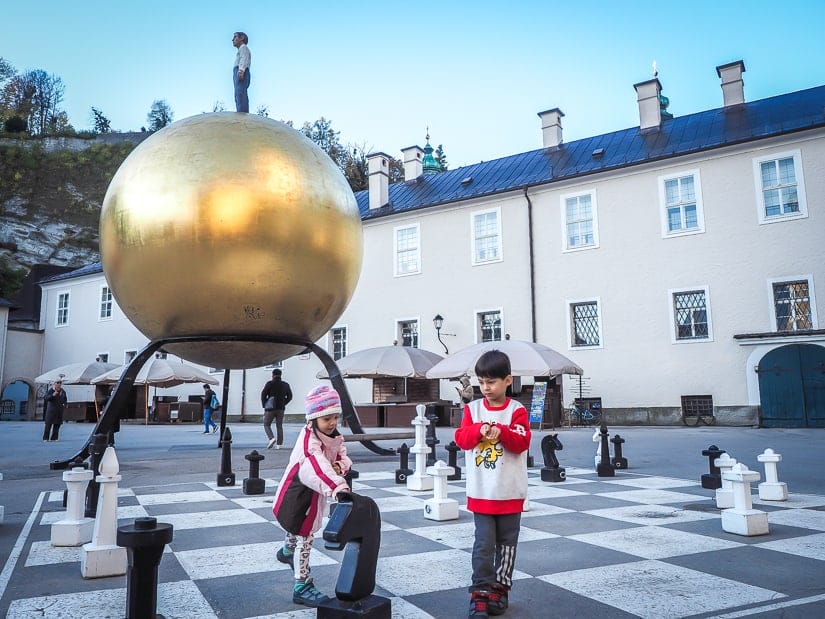 Our kids playing with the giant chess set at the Golden Sphere Statue, or Sphaera (Goldene Kugel), in Kapitelplatz, Salzburg.