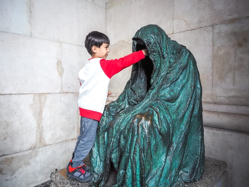 My son reaching into a hallow statue on Kapitelplatz Square in Salzburg