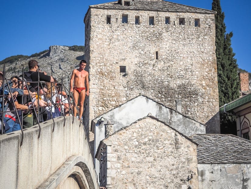 A Mostar bridge diver standing on Stari Most and waiting for donations to jump