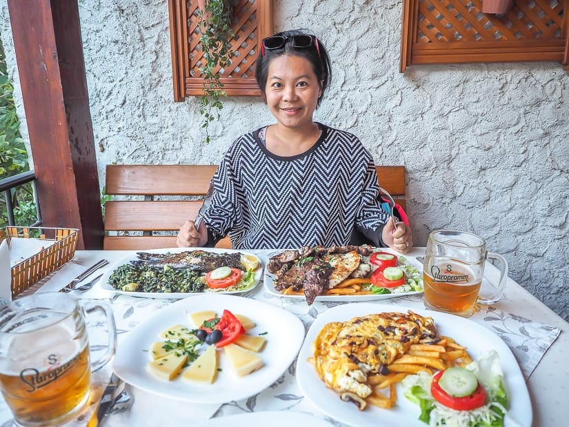 My wife with several plates of food in front of her in a restaurant in Mostar