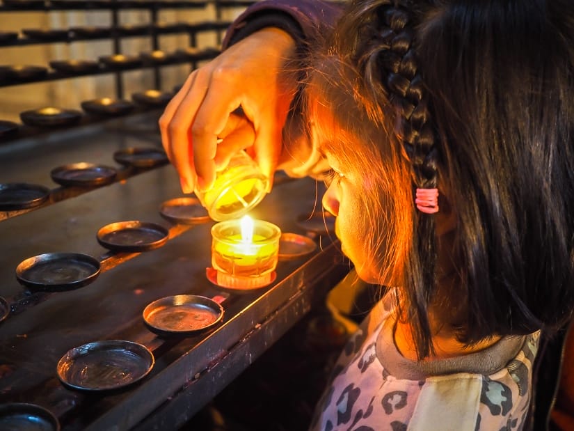 My daughter lighting a candle when we visited Salzburg Cathedral with kids