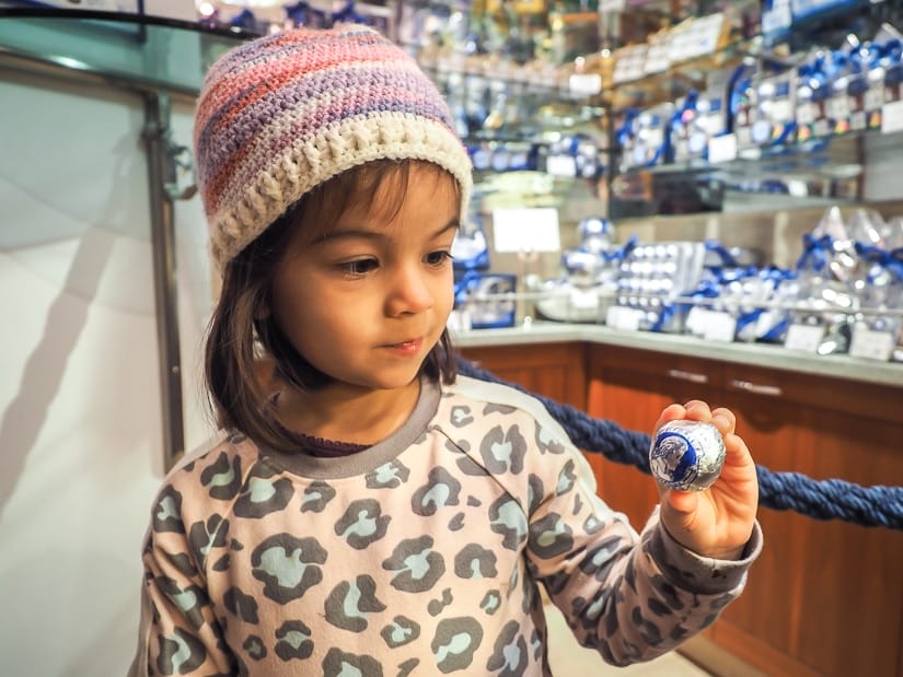 My daughter holding up a Mozart chocolate ball in Confiserie Fürst, a chocolate shop in Salzburg, one of the best places to visit in Austria with kids