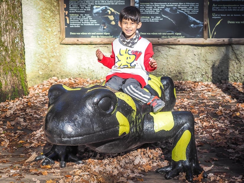 My son riding on a fire salamander statue at Salzburg Zoo