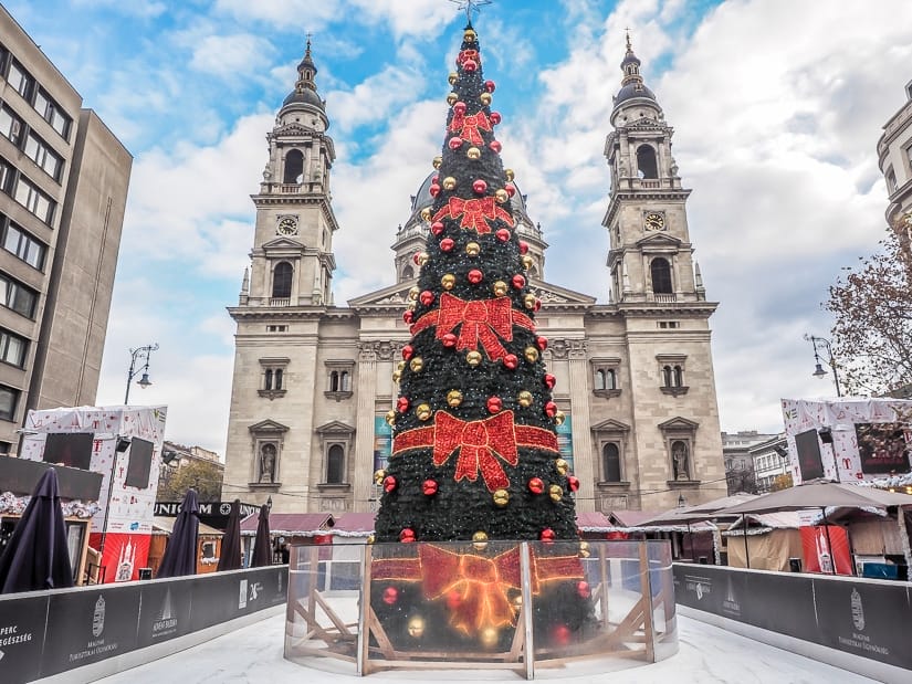 A Christmas tree with a children's skating rink around it with St. Stephen's Basilica Budapest in the background