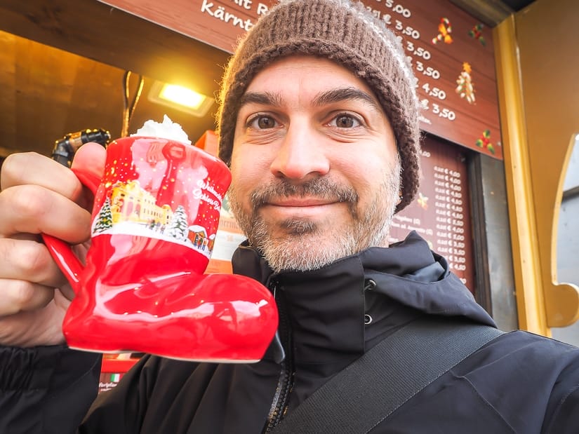 Me holding a stocking-shaped glass of hot egg nog at a Christmas market in Vienna, Austria