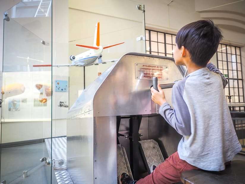 My son practicing flying an airplane at the Deutsches Museum, one of the best places to visit in Munich with kids