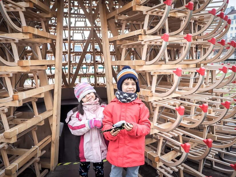 Our kids in front of a Christmas tree made of wooden sleds. Read on to find out the best places to visit in Vienna in winter with kids!