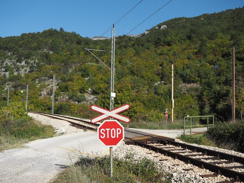 Stop sign that indicates where to cross the train tracks to find the entrance to the walking trail to Ostrog Monastery