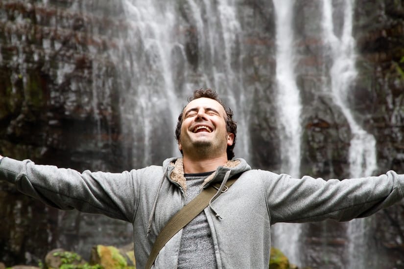 Man standing with arms open in front of Wufengqi Waterfall in Jiaoxi, Yilan