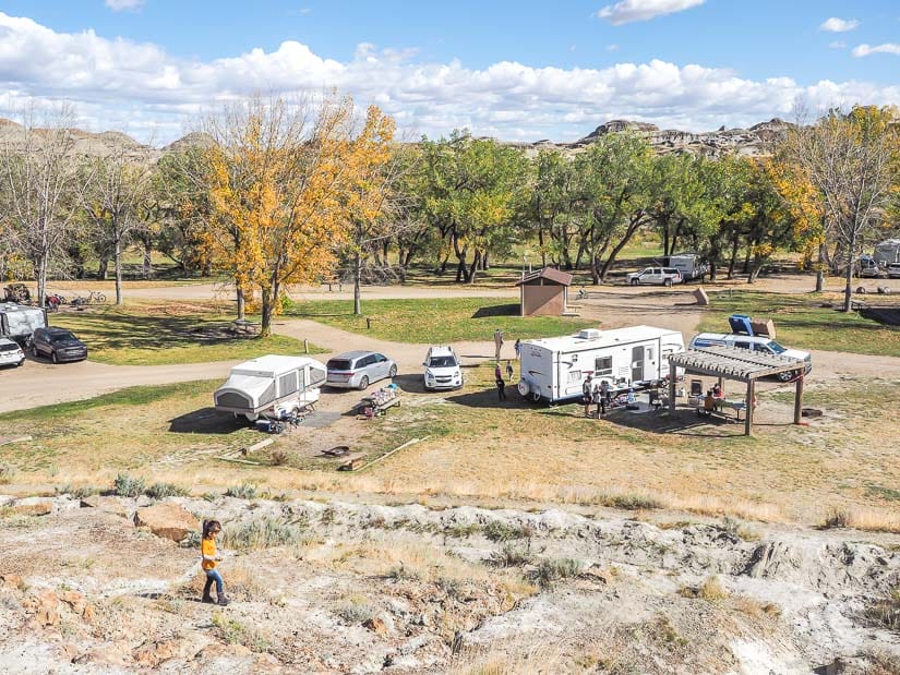 Campsite at Dinosaur Provincial Park, with a young girl walking on the rocky hill in the foreground