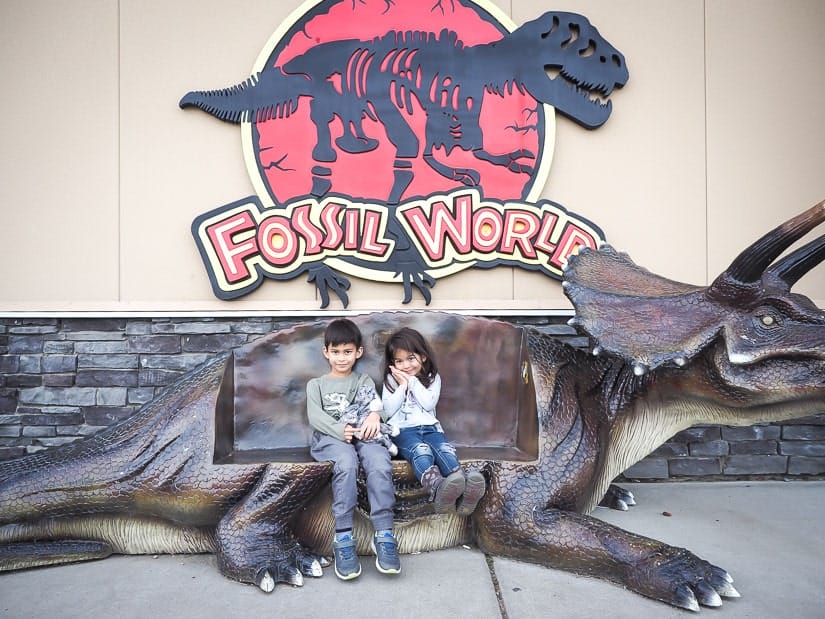 Our kids sitting on a dinosaur bench outside of Fossil World Discovery Center in Drumheller