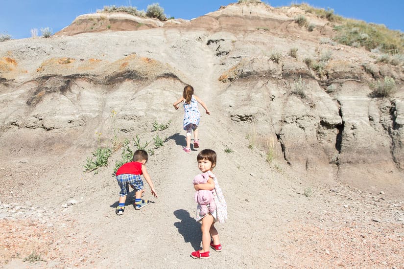 Some kids climbing badlands hills beside Little Church in Drumheller