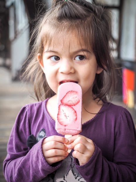Young girl licking a strawberry popsicle 