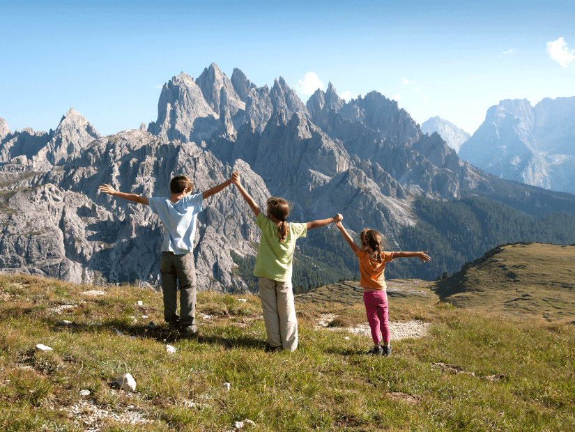 Three kids looking at an impressive mountain view in the Dolomites italy