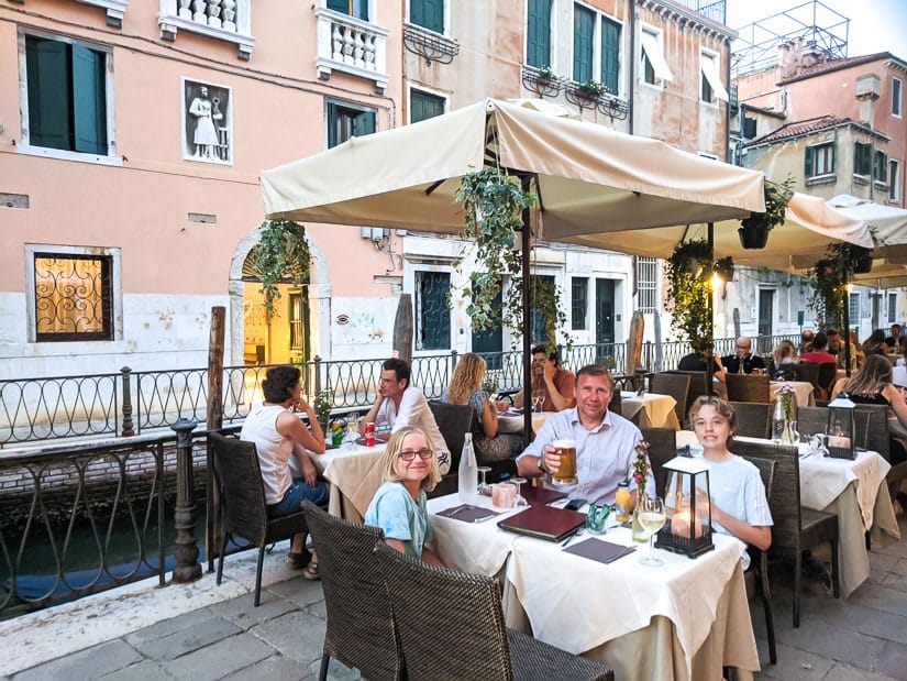 A family of travelers having a meal beside a canal in Venice
