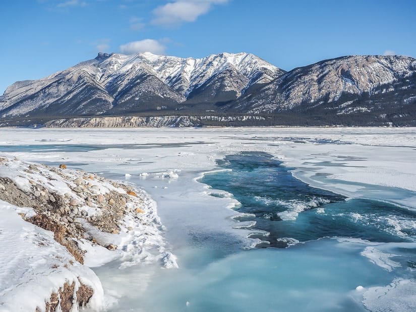 View of Abraham Lake frozen with blue water running through middle