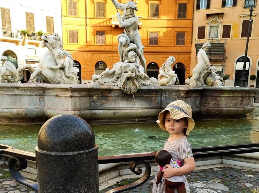 A toddler in front of a famous fountain in Rome