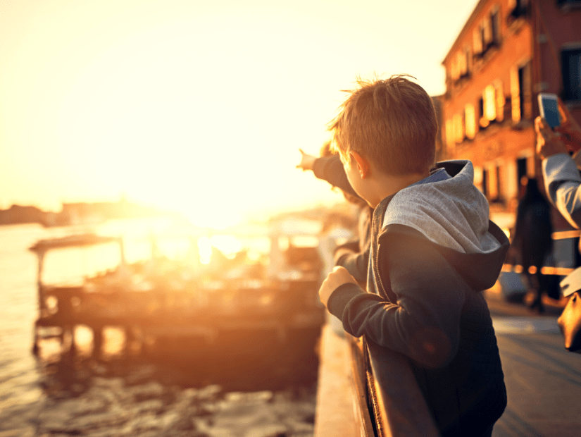 A kid looking over a canal in Venice at sunset