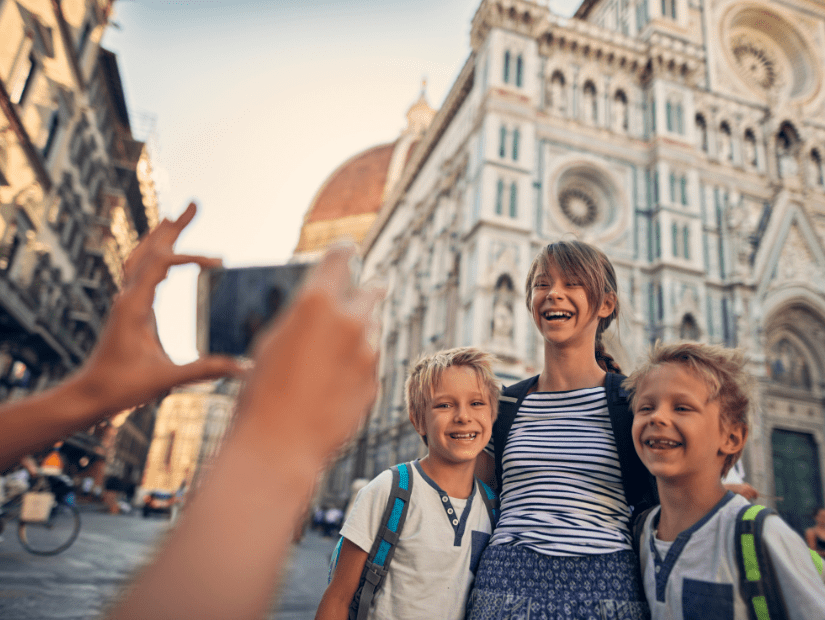 Some kids posing for a picture in Florence with ancient architecture behind them