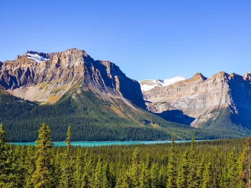 A thin turquoise strip of Hector Lake, with trees on the bottom and mountains in the background.