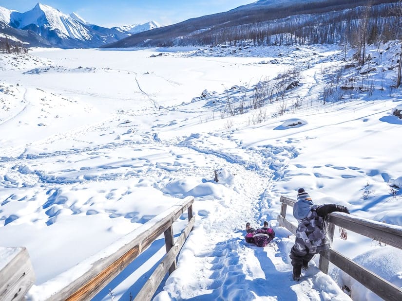 Two kids sliding down a snowy staircase at Medicine Lake in winter