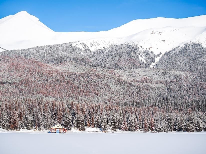 A cabin on the side of snow-covered Maligne Lake in winter