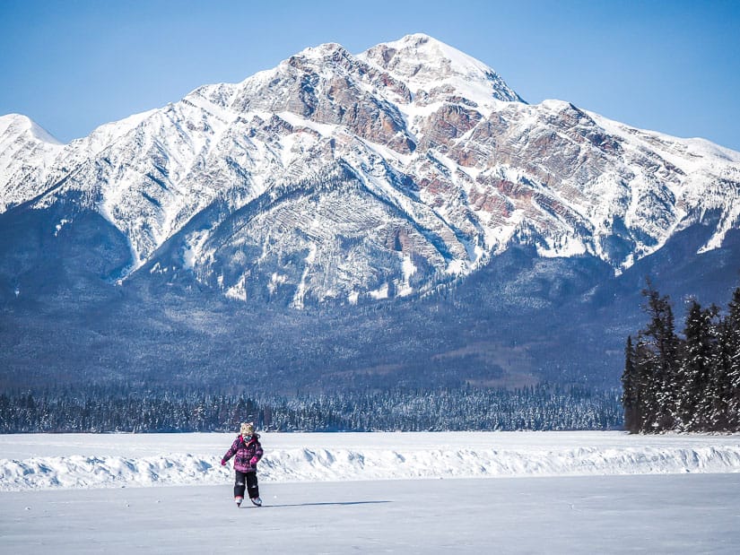 A young girl ice skating on Pyramid Lake in Jasper in winter with Mt. Pyramid in the background