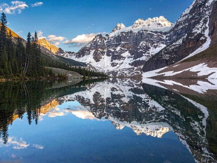 Mountain peaks reflection on the water at Upper Consolation Lake, which can be hiked to from Moraine Lake in Banff National Park