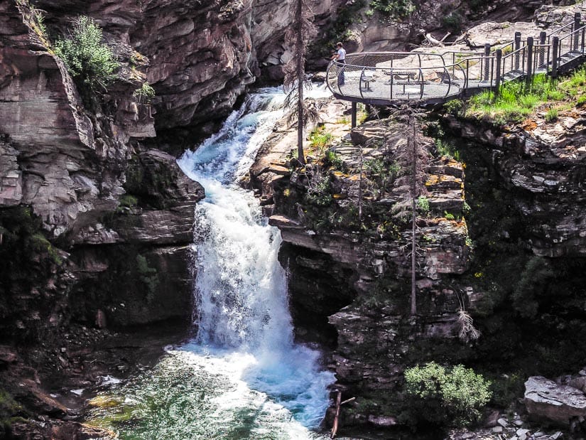 A person standing on a viewing platform looking at Blakiston Falls in Waterton.
