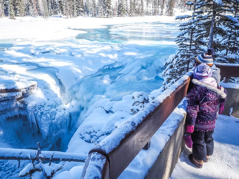Two kids looking down at Athabasca Falls in winter