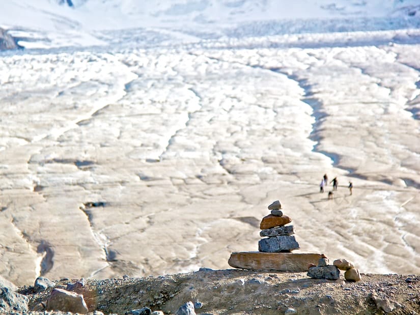 A rock man and people walking on the toe of Athabasca Glacier