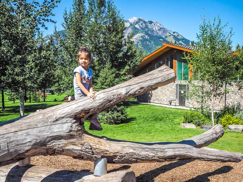 A girl climbing a log in Banff Central Playground