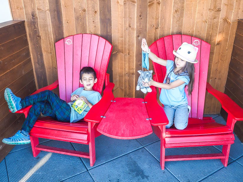 Two kids sitting in Parks Canada Red Chairs at Banff Gondola station