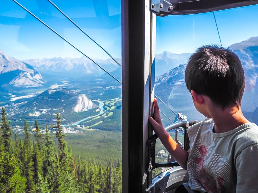 A kid riding the Banff Gondola and looking down at Banff town