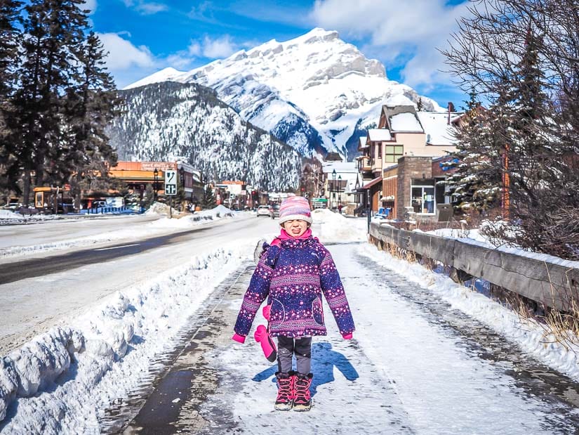 A kid standing on Bow River Bridge with Banff town in the background