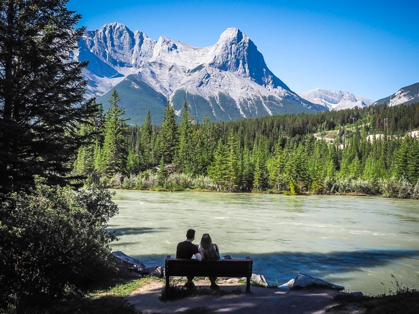 A couple sitting by the Bow River in Canmore