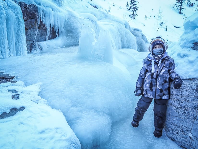 A kid standing on a frozen stream in Maligne Canyon