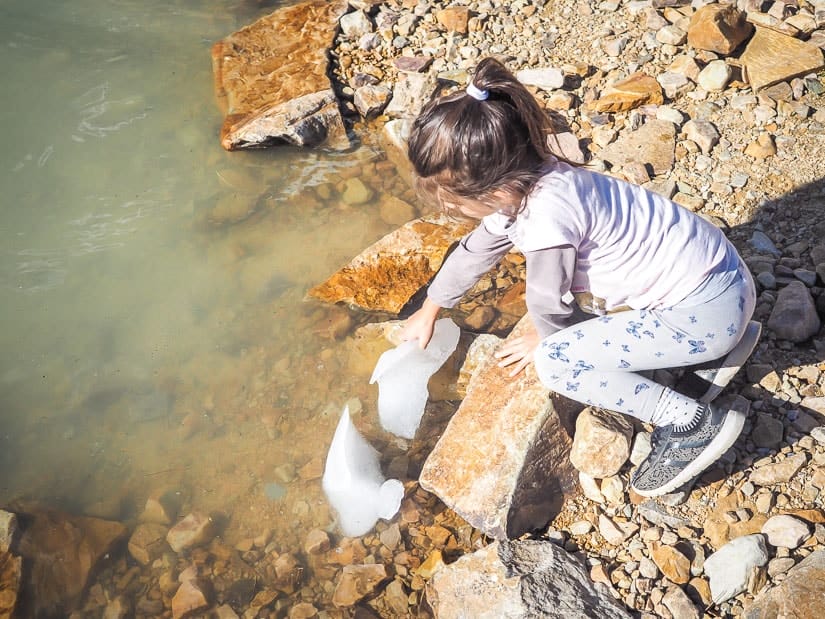 A girl grabbing a piece of ice in Cavell Pond