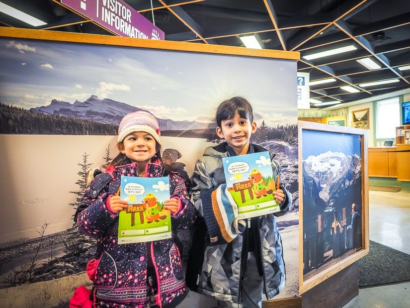Two kids holding children's activity booklets in Banff Visitor's Centre
