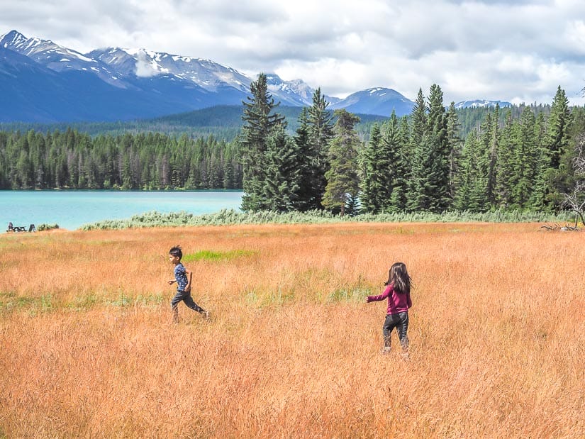 Two kids running around beside Lake Annette in Jasper