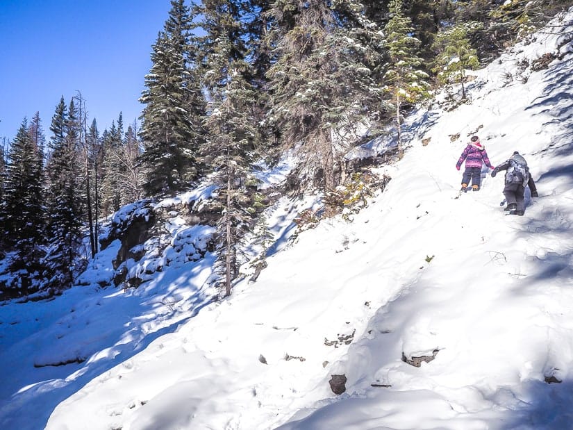 Two kids walking up a snowy trail